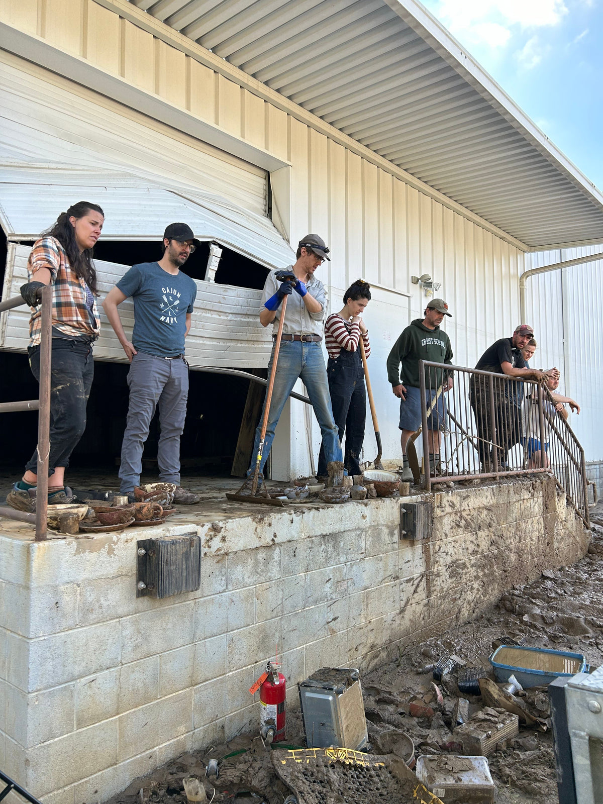People standing outside a white building surveying the damage after a flood