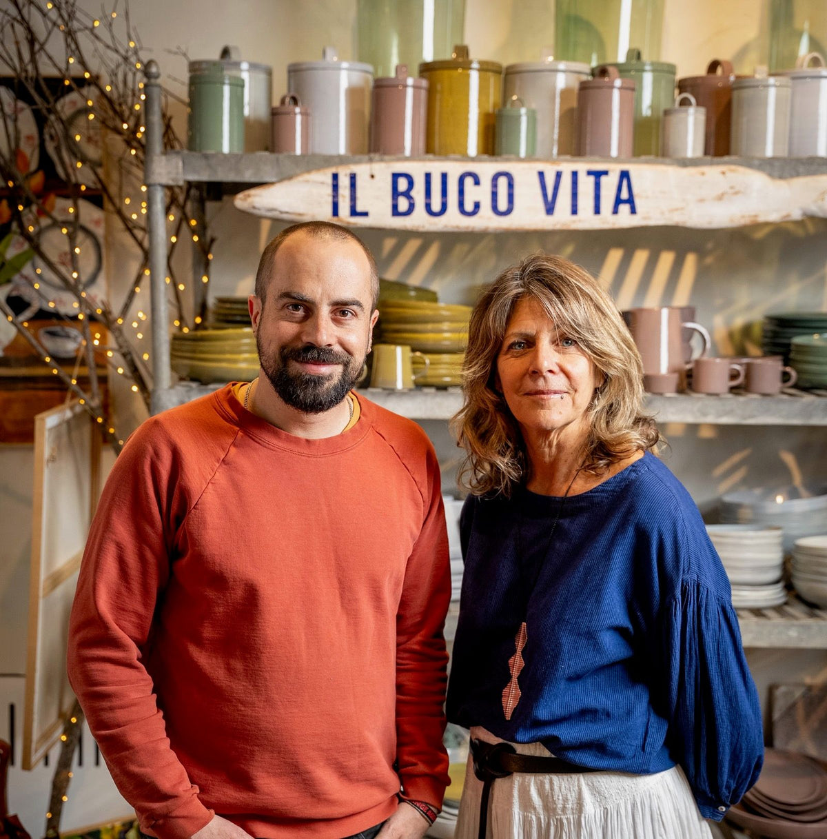 Alex Matisse and Donna Lennard standing together in front of a shop display with a sign that reads 'il Buco Vita' above them.