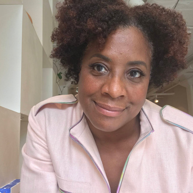 Donna is wearing a blush pink top and smiling at the camera