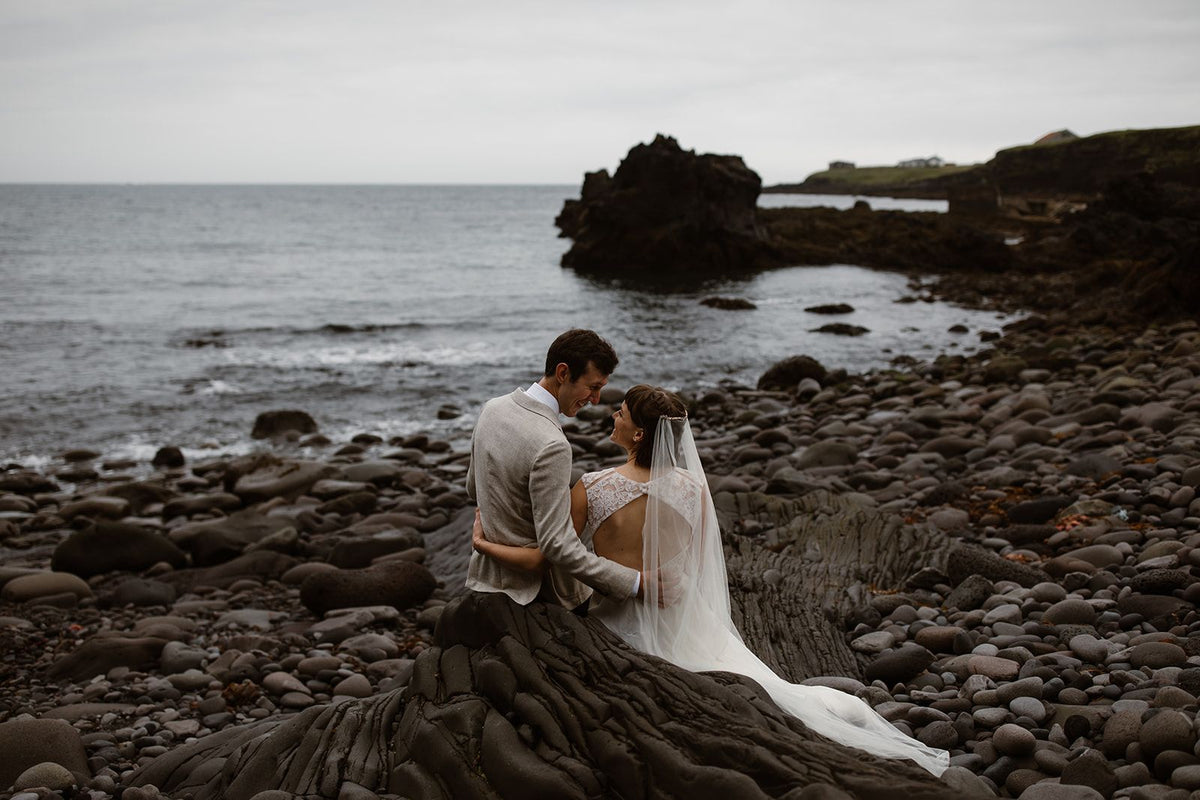 A wedding photo of Eva and James on the coast looking at each other.
