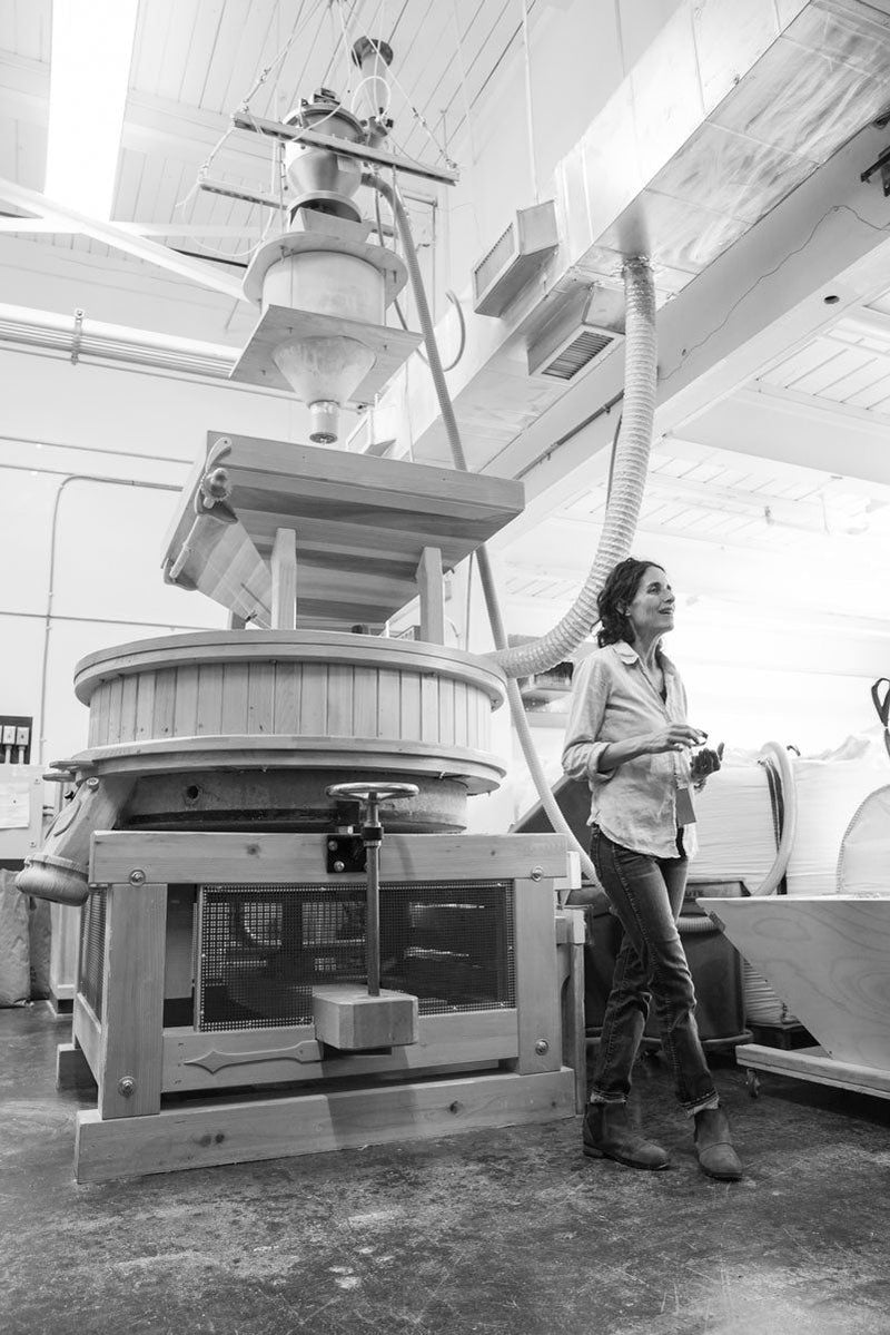 A black and white photo of Jennifer next to a commercial flour mill