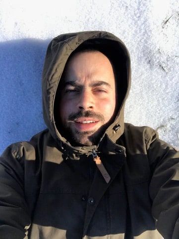 Alex wearing a coat and laying on the snow