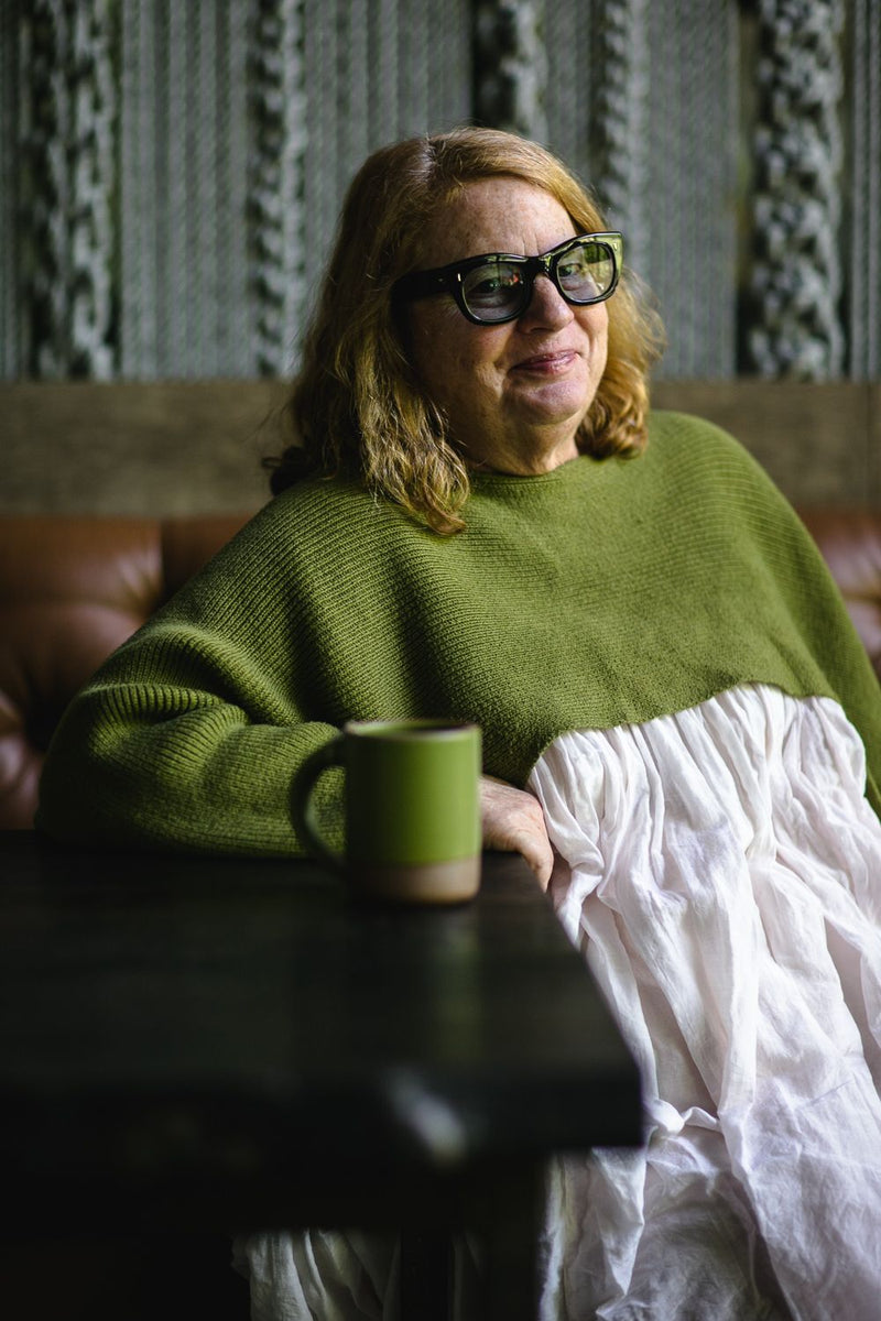 Chef and restaurateur Anne Quatrano wearing a fern green sweater with a matching mug on the table.