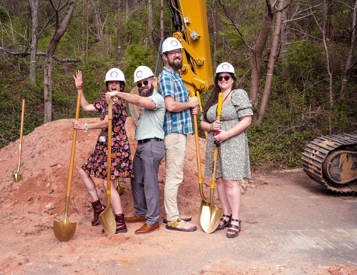 4 people standing at a worksite with shovels
