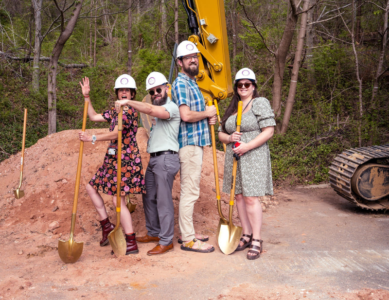 4 people standing at a worksite with shovels