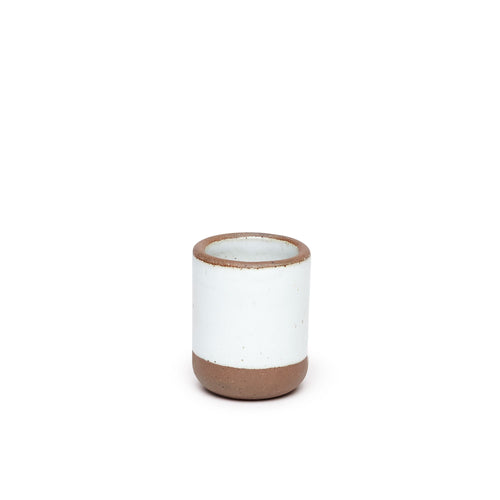 A short ceramic cup in a cool white color featuring iron speckles and unglazed rim.