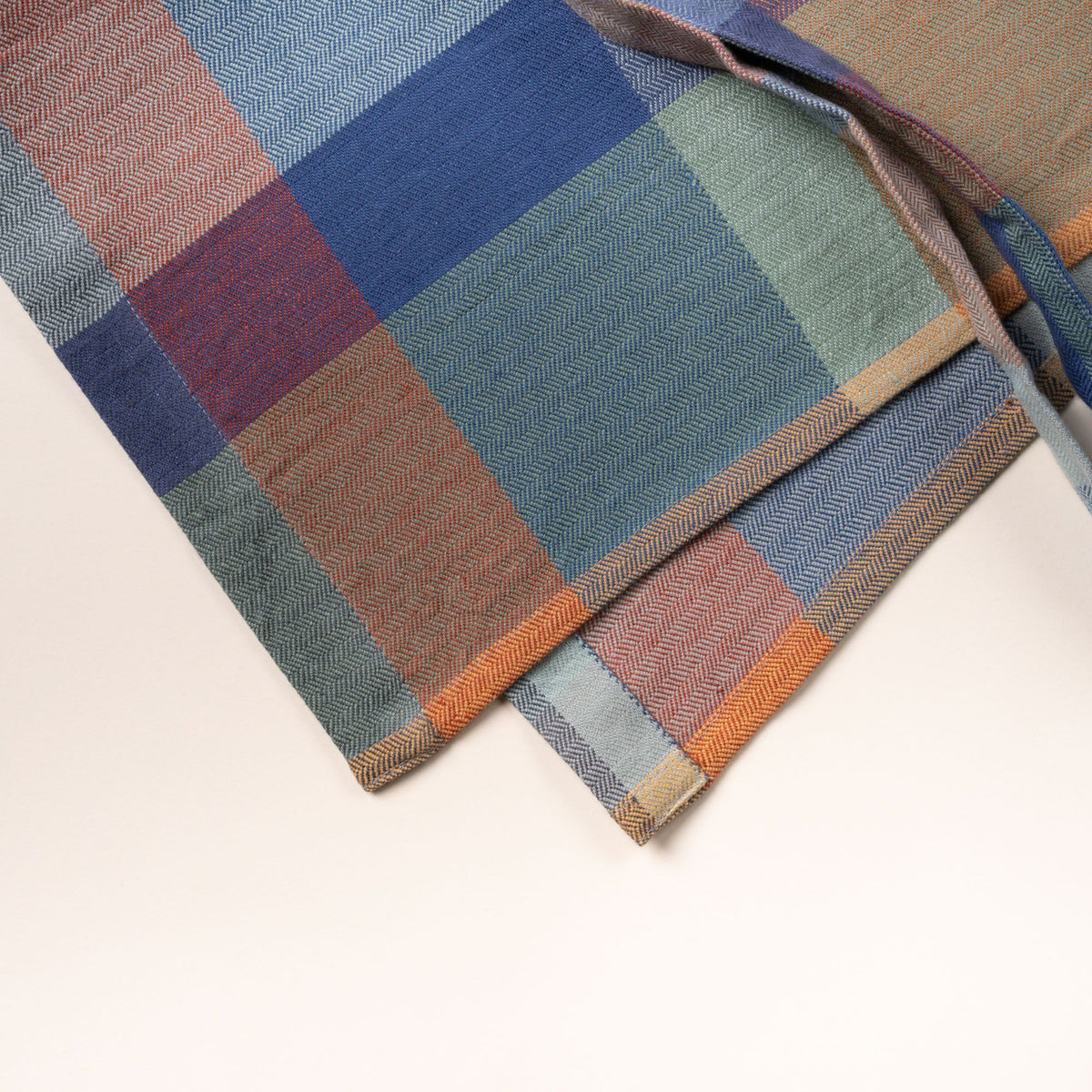 Closeup of the fabric of a plaid kitchen apron in muted blue, green, and tan tones