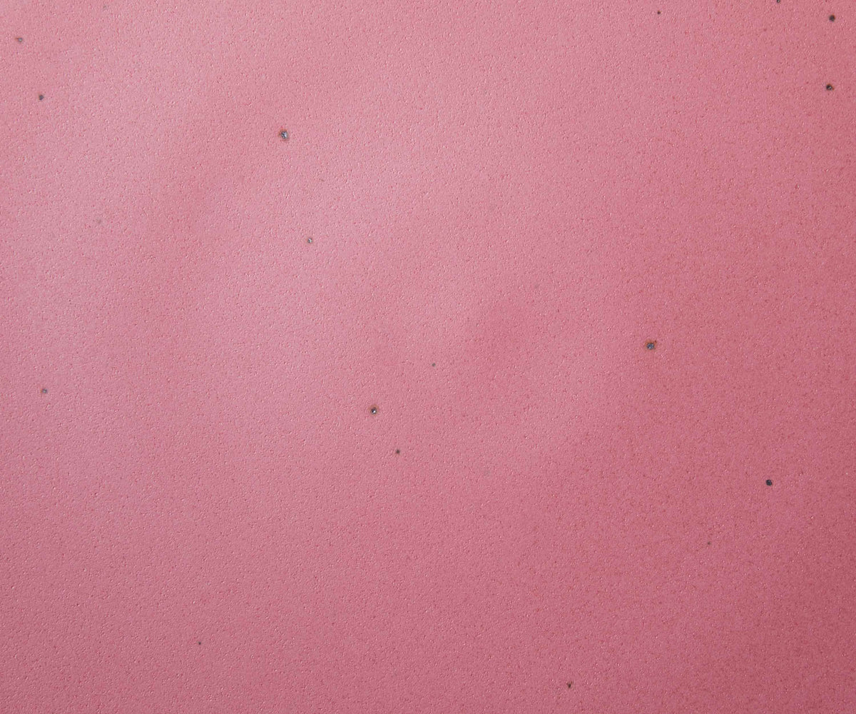 A closeup of a ceramic plate in a pink color featuring iron speckles