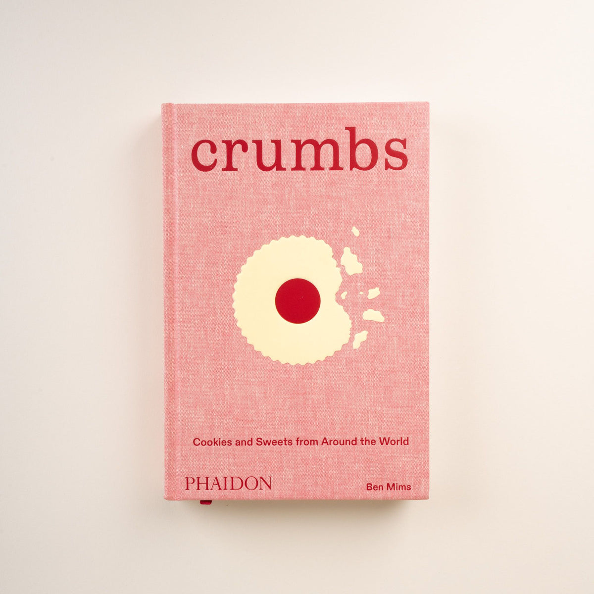 Front cover of 'Crumbs: Cookies and Sweets from Around the World' by Ben Mims, pink with cookie illustration.