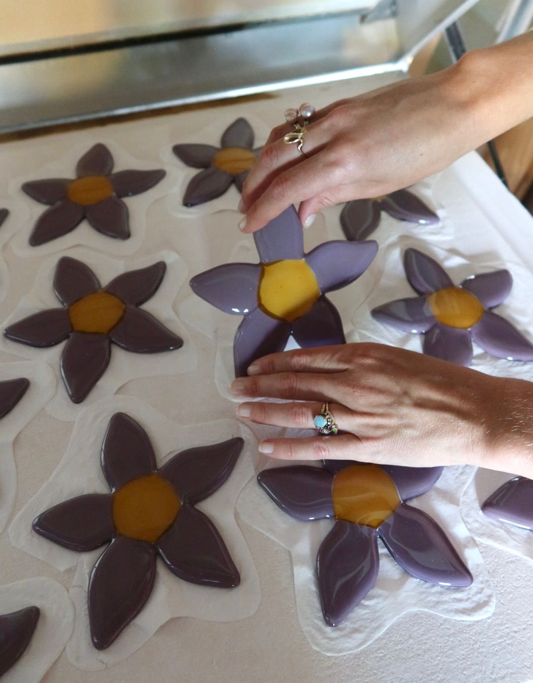Two hands working on creatingthe glass flower candleholder.