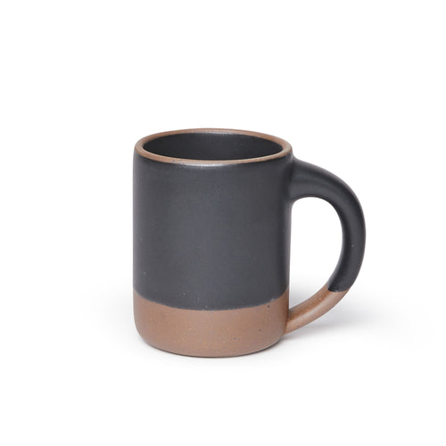 A big sized ceramic mug with handle in a graphite black glaze featuring iron speckles and unglazed rim and bottom base.