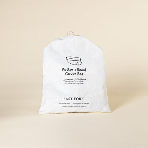 White fabric bag labeled "Potter’s Bowl Cover Set" from East Fork, displayed against a beige background, indicating it includes covers for various bowl types.