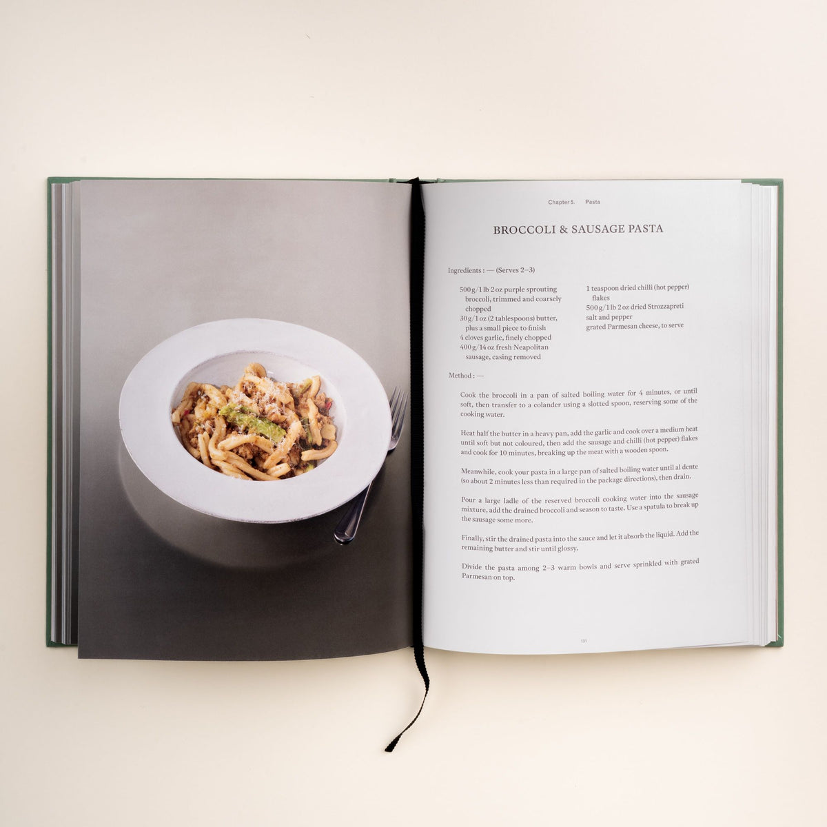 Open cookbook showing broccoli and sausage pasta recipe with a photo of the plated pasta on the left page.