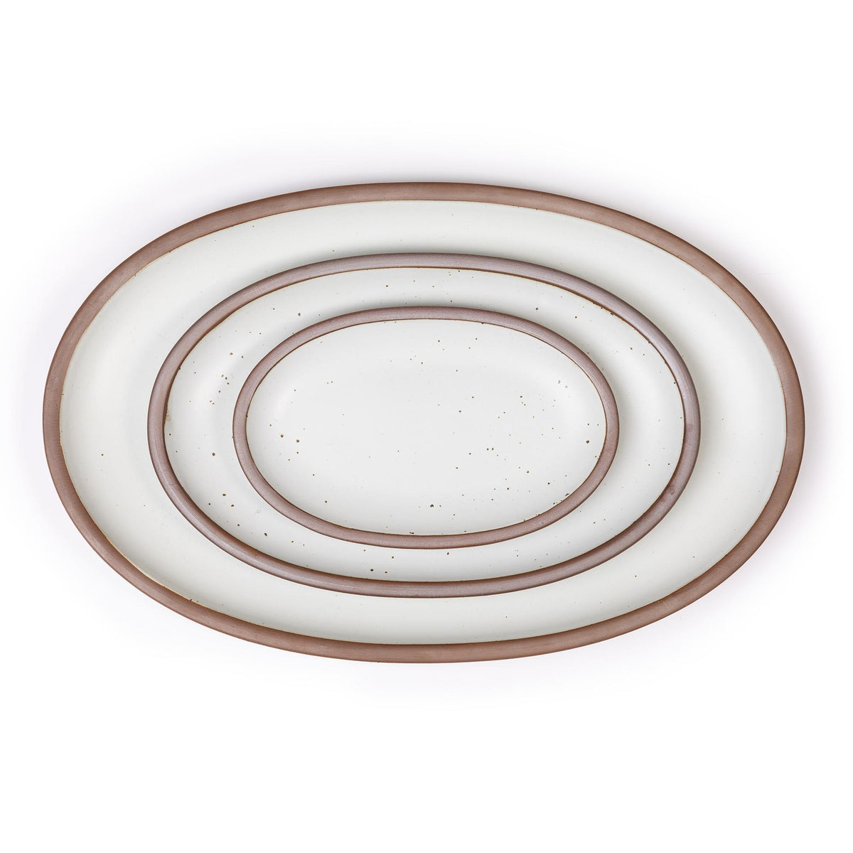 Set of three white ceramic oval platters with unglazed rim nested together on a white background