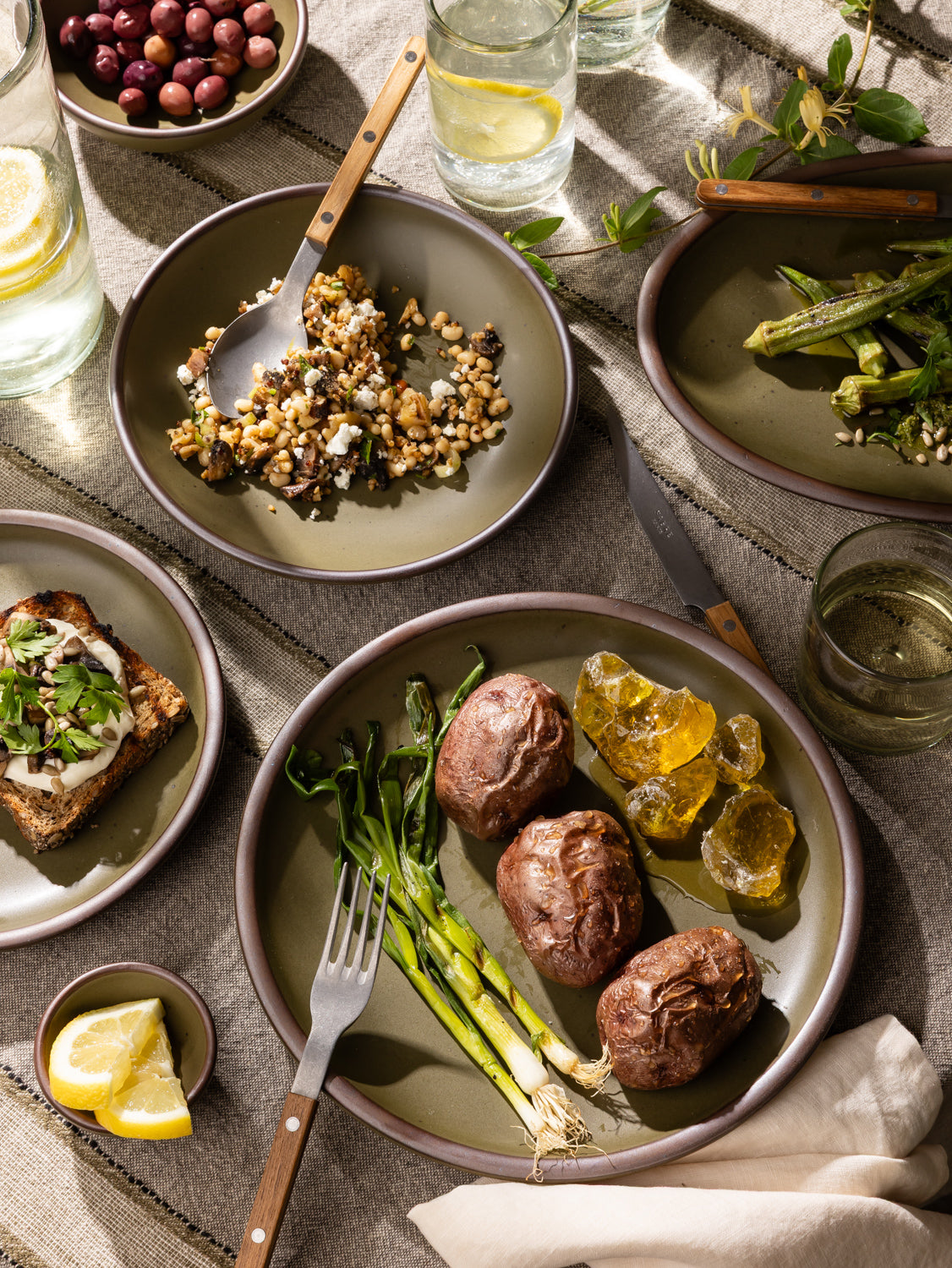 Dinner table setting with plates of food, glasses of water, and a fork.