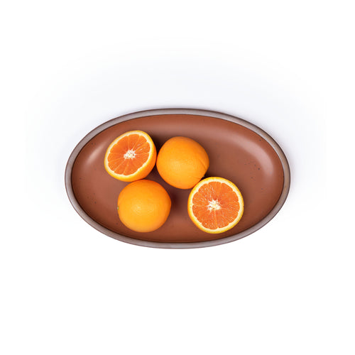 A small oval ceramic platter in a cool terracotta color featuring iron speckles and an unglazed rim, with oranges