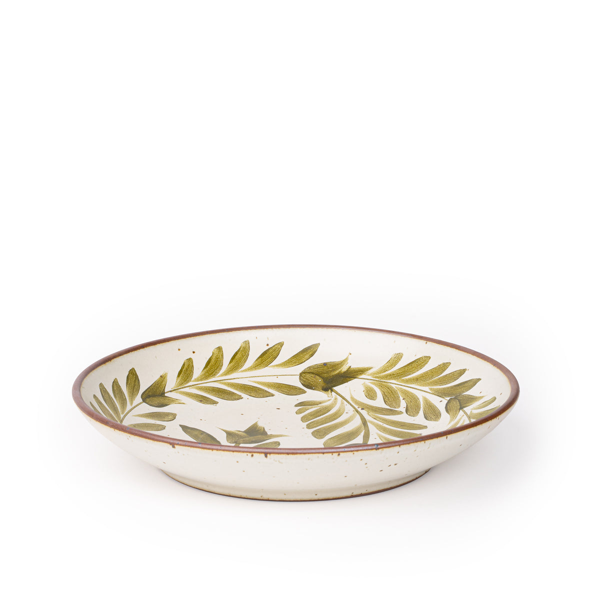 A large ceramic plate with a curved bowl edge in a warm, tan-toned, off-white color featuring iron speckles and an unglazed rim, with handpainted greenery in an olive green color.