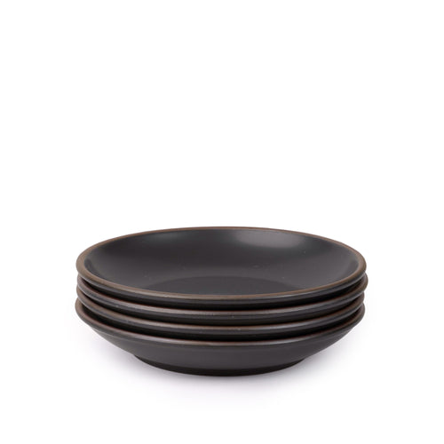A stack of 4 medium ceramic plates with a curved bowl edge in a graphite black color featuring iron speckles and an unglazed rim.