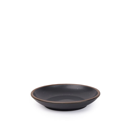 A small ceramic plate with a curved bowl edge in a graphite black color featuring iron speckles and an unglazed rim.