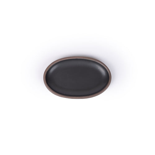 A small oval ceramic platter in a black color featuring iron speckles and an unglazed rim