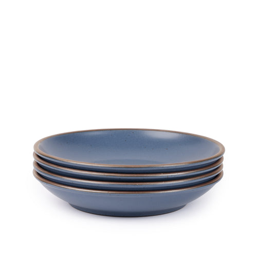A stack of 4 large ceramic plates with a curved bowl edge in a blue color featuring iron speckles and an unglazed rim.