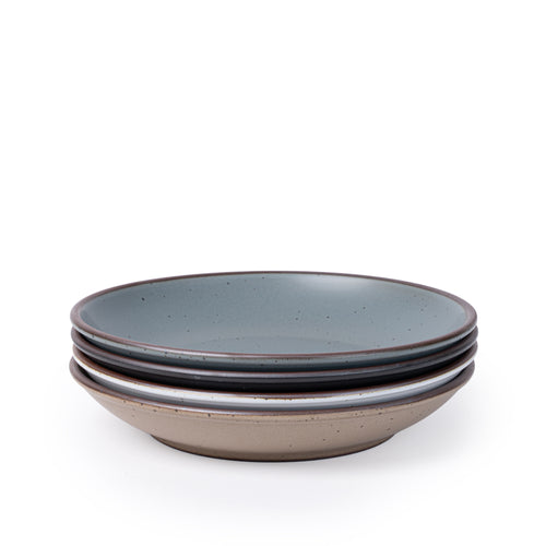 A stack of 4 large ceramic plates with a curved bowl edge featuring iron speckles and an unglazed rim in blue-grey, graphite black, cool white, and pale warm brown.