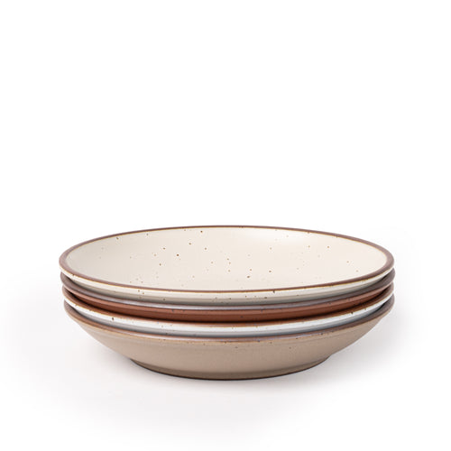 A stack of 4 large ceramic plates with a curved bowl edge featuring iron speckles and an unglazed rim in warm off-white, cool terracotta, cool white, and pale warm brown colors.