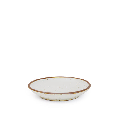 A small ceramic plate with a curved bowl edge in a cool white color featuring iron speckles and an unglazed rim.
