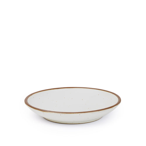 A medium ceramic plate with a curved bowl edge in a cool white color featuring iron speckles and an unglazed rim.