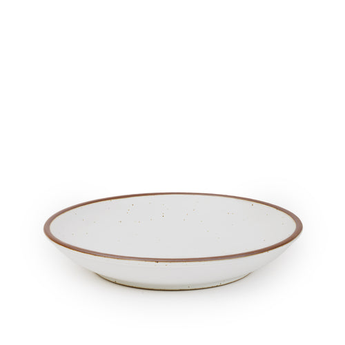 A large ceramic plate with a curved bowl edge in a cool white color featuring iron speckles and an unglazed rim.