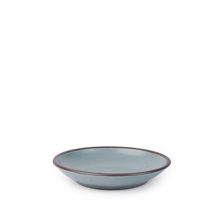 A small ceramic plate with a curved bowl edge in a blue-grey color featuring iron speckles and an unglazed rim.