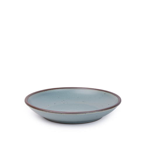 A medium ceramic plate with a curved bowl edge in a blue-grey color featuring iron speckles and an unglazed rim.