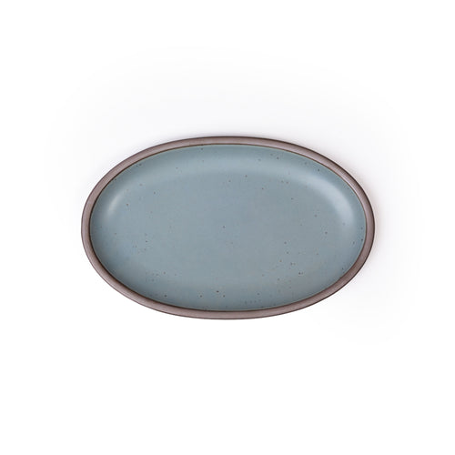 A medium oval ceramic platter in a blue-grey color featuring iron speckles and an unglazed rim