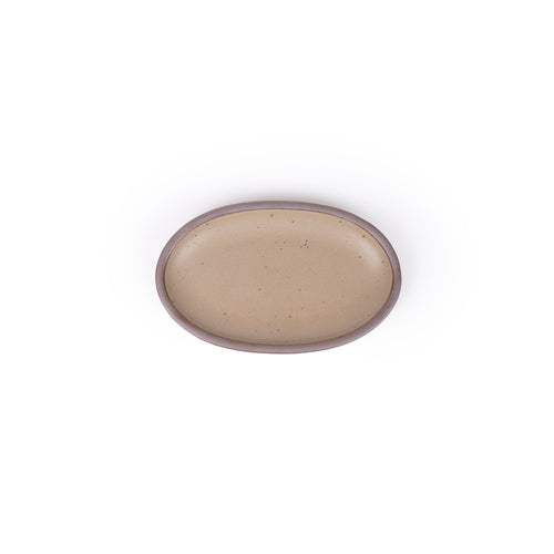 A small oval ceramic platter in a pale warm brown color featuring iron speckles and an unglazed rim