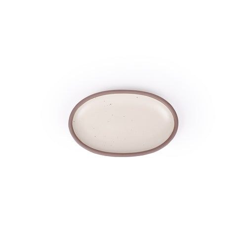 A small oval ceramic platter in a warm off-white color featuring iron speckles and an unglazed rim
