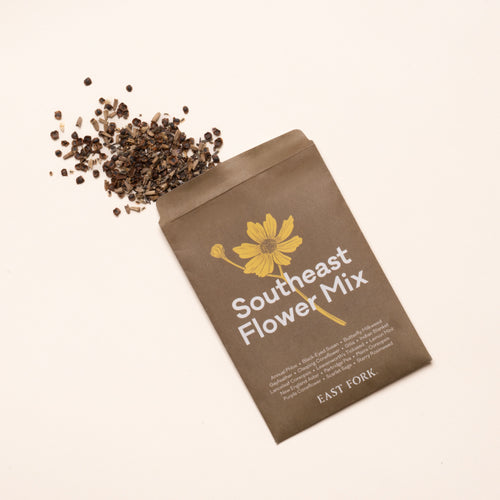 Southeast flower mix seed packet with yellow flower illustration and scattered wildflower seeds on a light background