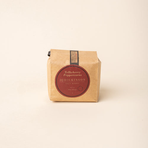 Bag of J.Q. Dickinson Tellicherry Peppercorns on a plain white background.