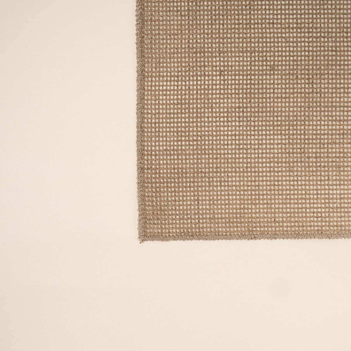 Corner of a Textured woven placemat in a natural neutral color