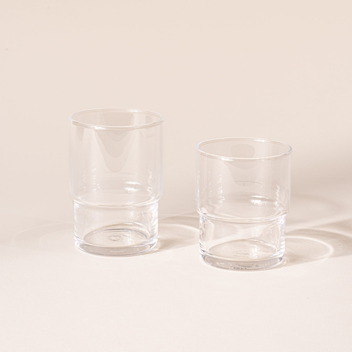A small and medium clear cylindrical glass with a wider top half with a narrower bottom half