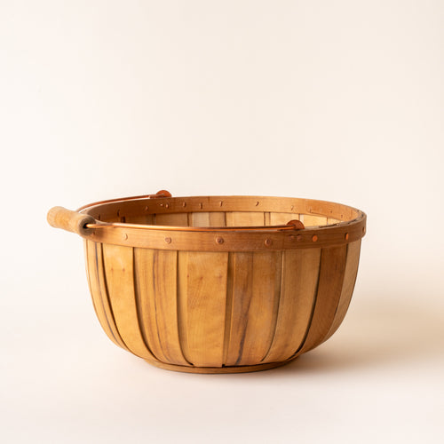 Round wooden gathering large basket with copper handle and rivet details, shown against a light background.