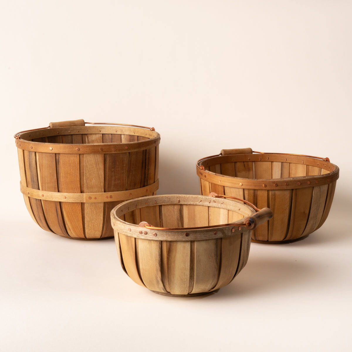 Three wooden baskets of different sizes on a beige background