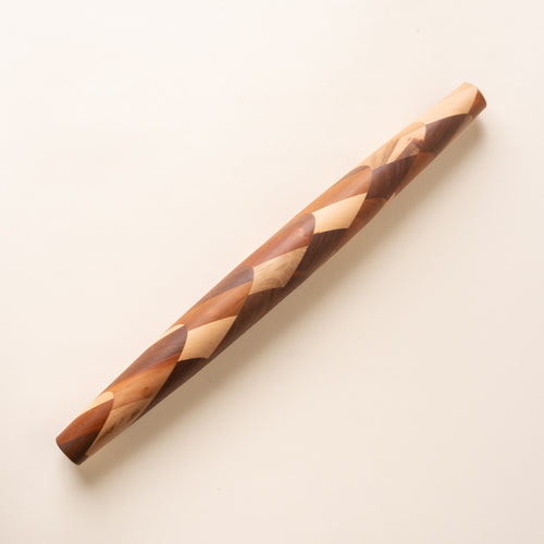 A mixed wood rolling pin that tapers on each end
