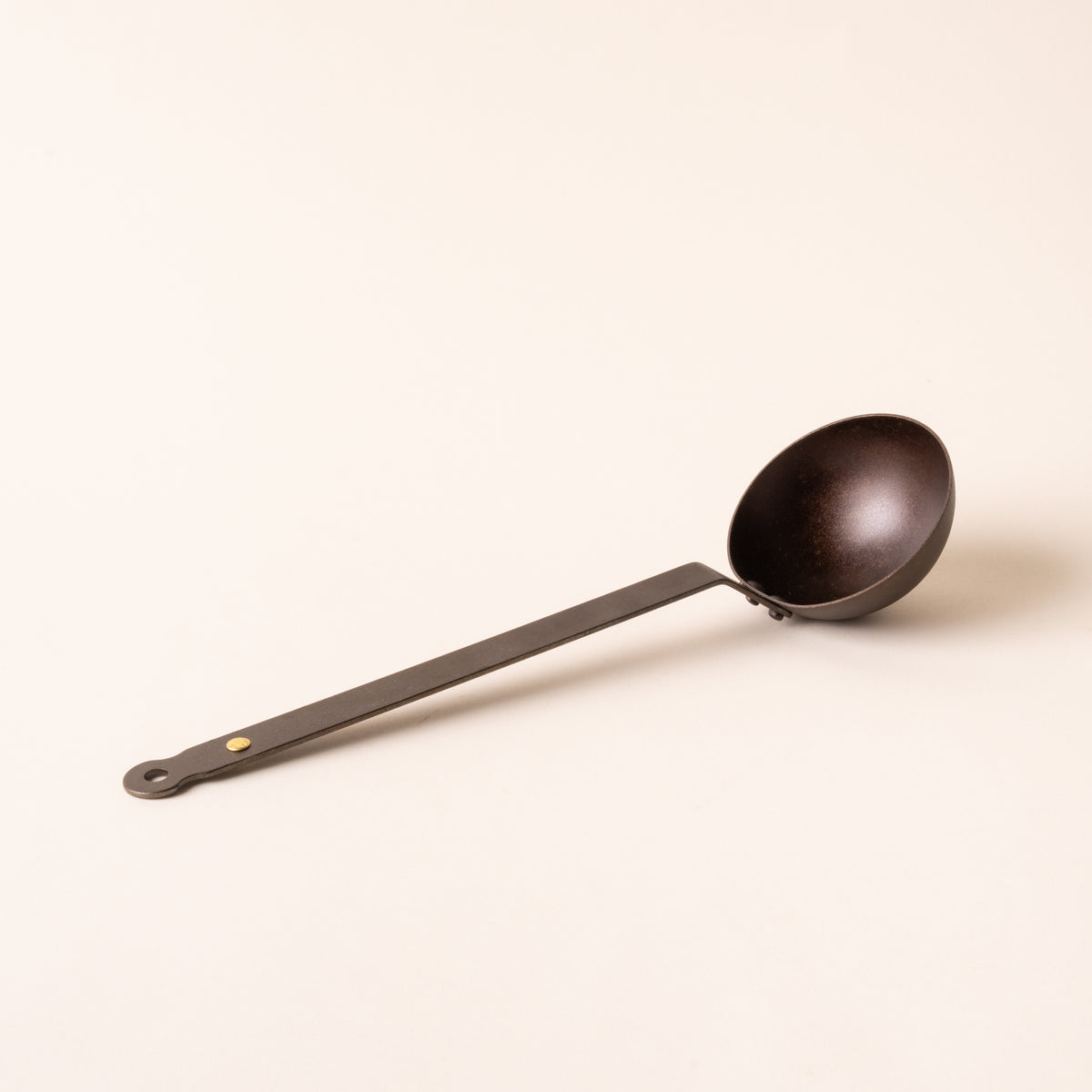 Black metal ladle with cup and a hole at the top of the handle