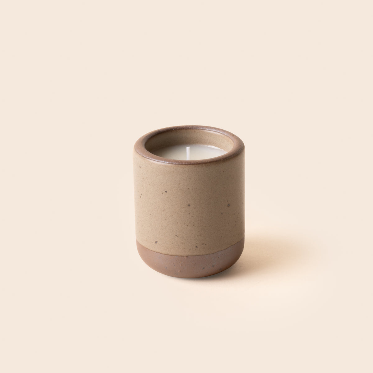 Small ceramic vessel in a warm pale brown color with candle inside.