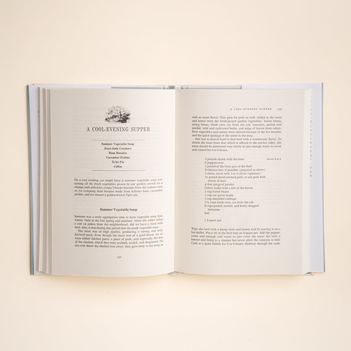An open hardcover cookbook spread showing a recipe page for 'A Cool Evening Supper' on warm off-white paper, photographed against a matching light cream background.