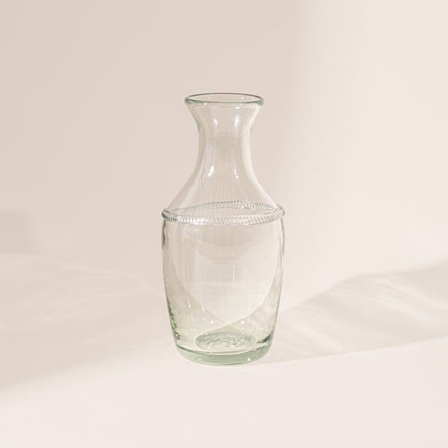 Clear glass bottle vase with a flared neck and decorative ring detail on a neutral background.