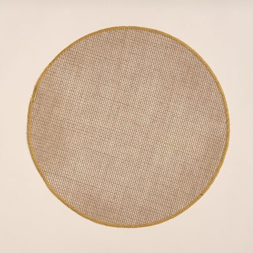Round woven placemat in a natural color with a sewn ochre rim on a beige background
