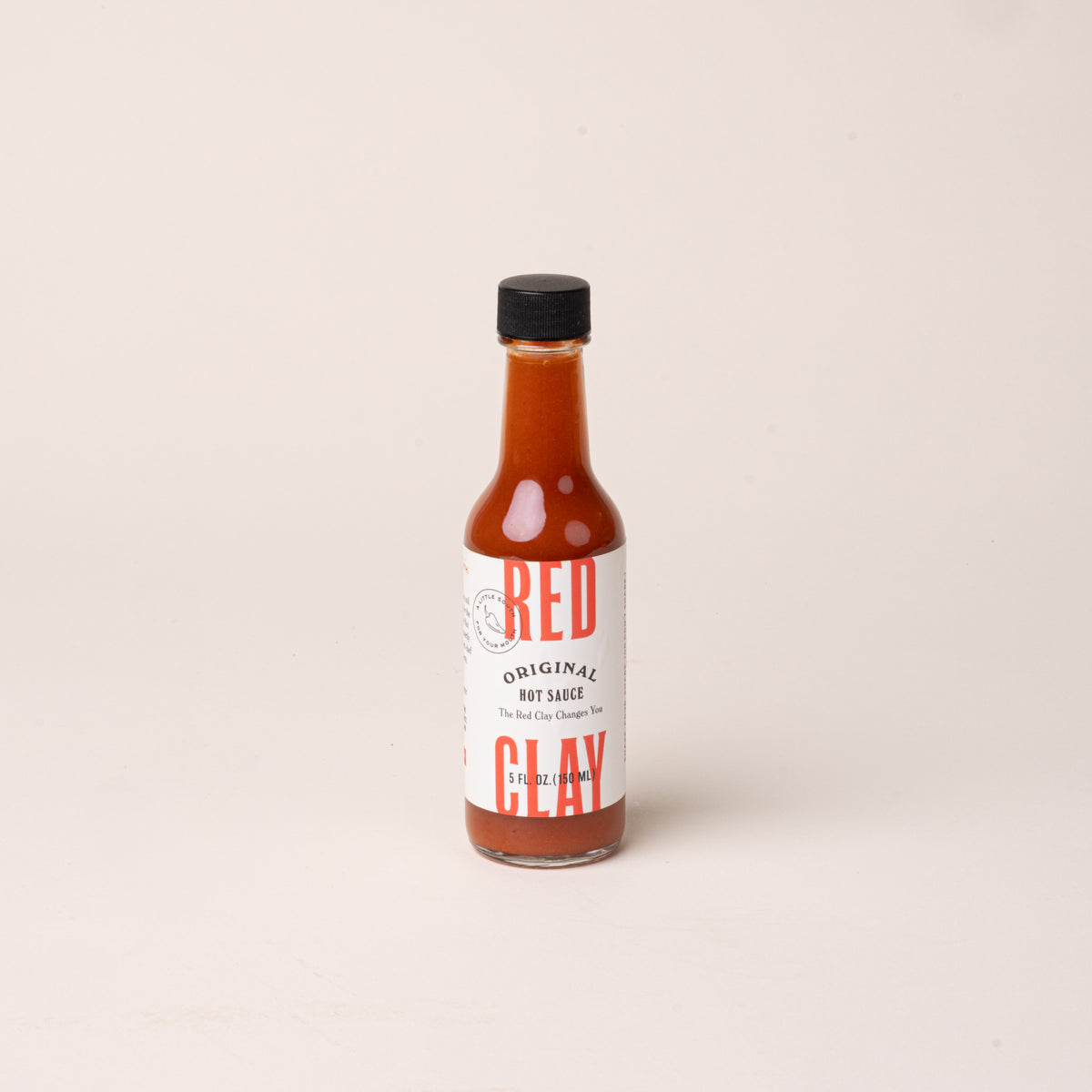 Bottle of Red Clay Original Hot Sauce with a white label and black cap.