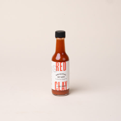 Bottle of Red Clay Original Hot Sauce with a white label and black cap.