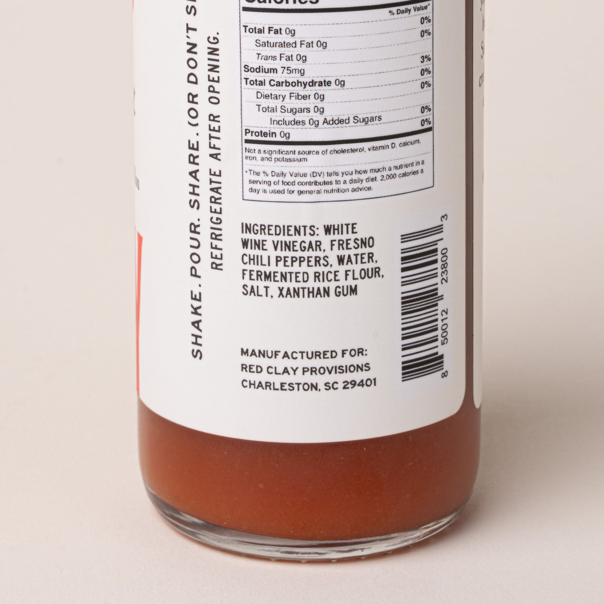 Close-up of the back label of a glass bottle containing an orange-brown liquid, showing nutrition facts, ingredients, and a barcode on a white label.